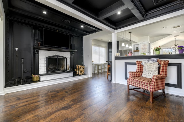 living area with visible vents, wood finished floors, coffered ceiling, and a fireplace