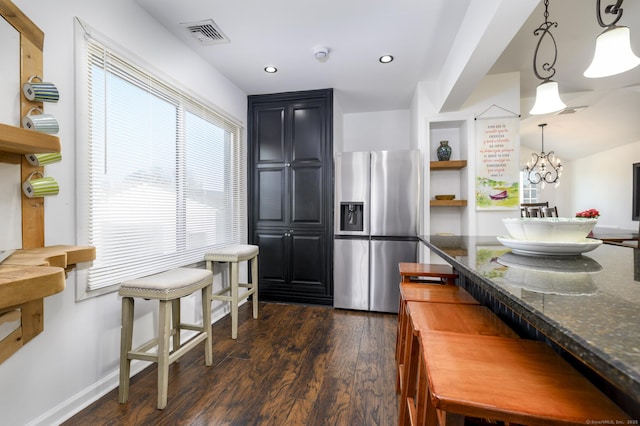 kitchen featuring dark wood finished floors, visible vents, dark stone countertops, and stainless steel fridge
