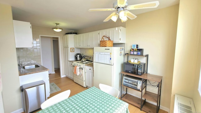 kitchen with a sink, light wood-style floors, white appliances, ceiling fan, and white cabinetry