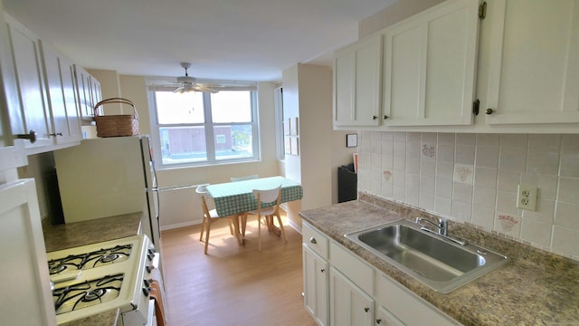 kitchen with light wood-style flooring, a sink, baseboards, a ceiling fan, and white appliances