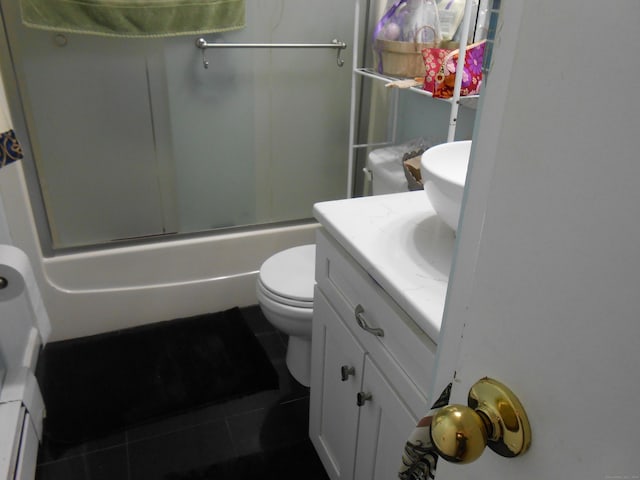 bathroom with combined bath / shower with glass door, toilet, tile patterned flooring, and vanity