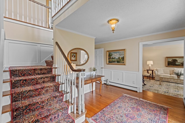 9 Academy Ln, Old Lyme, CT 06371 - staircase with baseboard heating, ornamental molding, wood finished floors, a decorative wall, and wainscoting
