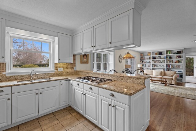 9 Academy Ln, Old Lyme, CT 06371 - kitchen with stainless steel gas stovetop, white cabinets, a peninsula, open floor plan, and a textured ceiling