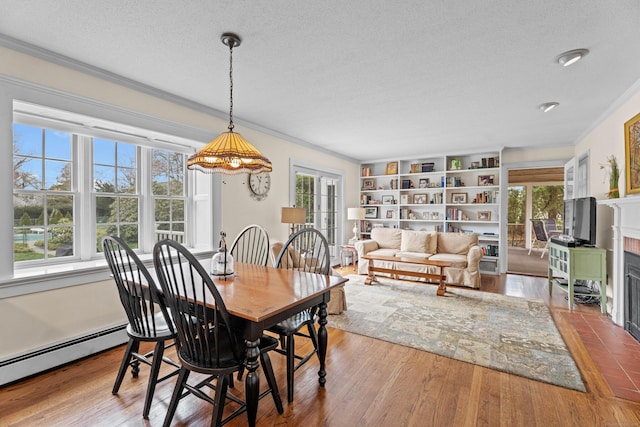 9 Academy Ln, Old Lyme, CT 06371 - dining space with a textured ceiling, ornamental molding, a baseboard radiator, a fireplace with flush hearth, and wood finished floors