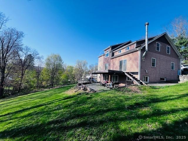 back of house featuring a lawn and stairs