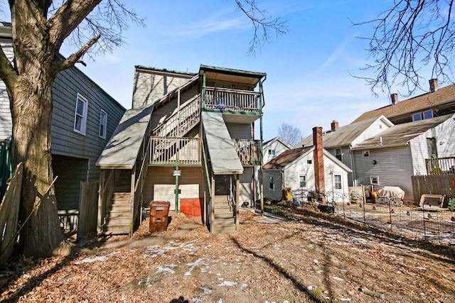 rear view of property with fence, a balcony, stairs, and a residential view