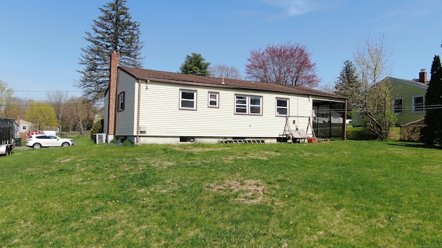 back of property with a chimney and a yard