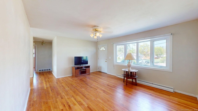 living room featuring a ceiling fan, a baseboard heating unit, visible vents, and light wood-type flooring