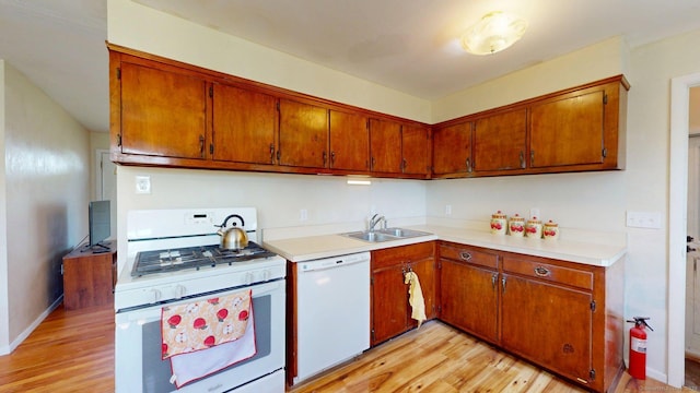 kitchen with white appliances, light countertops, a sink, and light wood-style floors