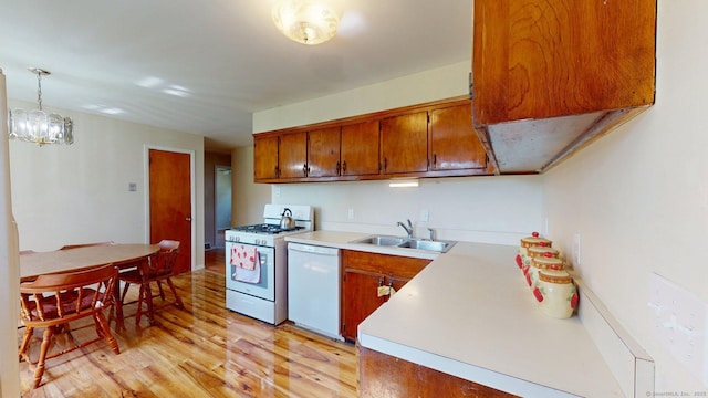 kitchen with white appliances, brown cabinets, a sink, and light wood-style floors