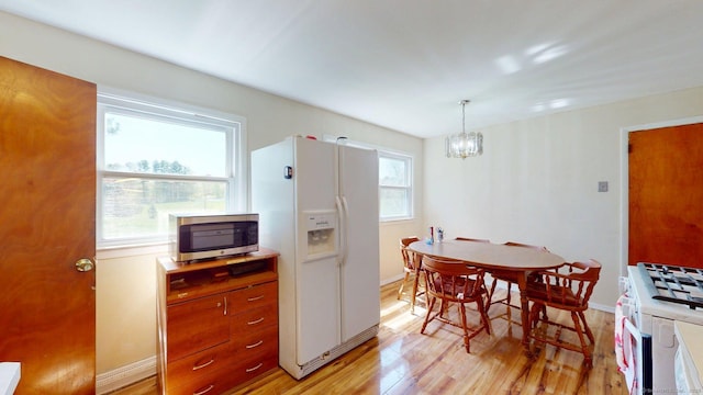 kitchen featuring brown cabinets, white appliances, a chandelier, light wood-style flooring, and baseboards