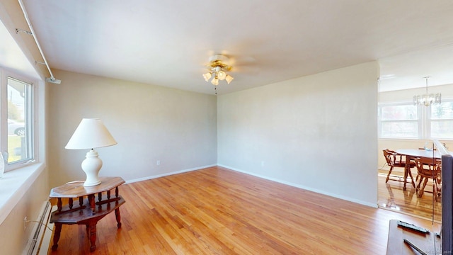 unfurnished room featuring light wood-type flooring, a baseboard radiator, and baseboards