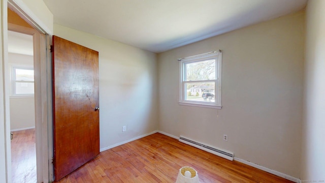 spare room with baseboards, a baseboard heating unit, and light wood finished floors
