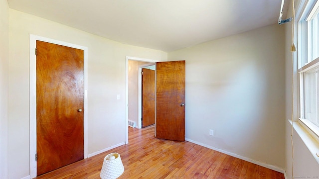 unfurnished bedroom with baseboards, multiple windows, light wood finished floors, and visible vents