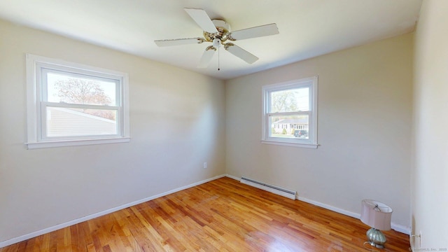 empty room with baseboards, a baseboard radiator, light wood finished floors, and ceiling fan