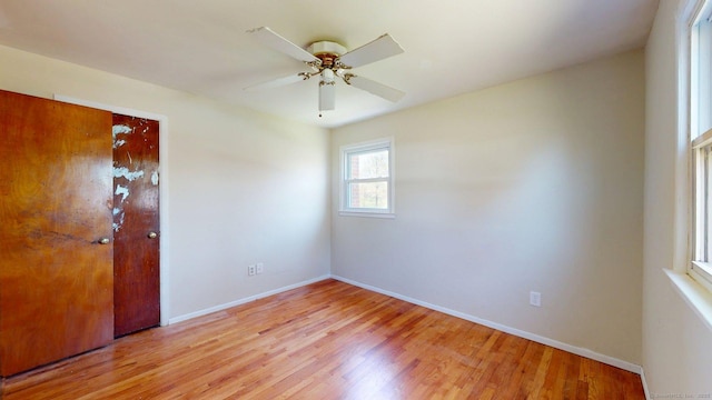 spare room with baseboards, ceiling fan, and light wood finished floors