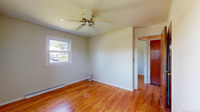 unfurnished room featuring baseboards, a ceiling fan, light wood finished floors, and a baseboard heating unit