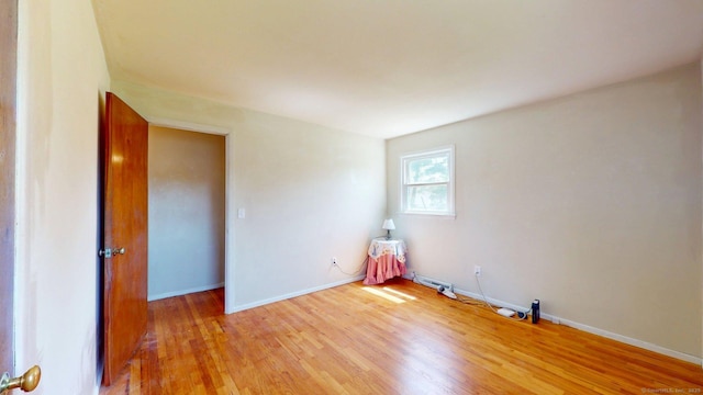 spare room featuring baseboards and light wood-style flooring