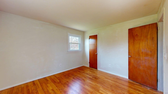 spare room featuring baseboards and light wood finished floors