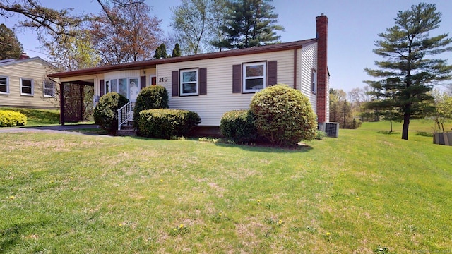 view of front of property featuring a chimney, central AC unit, and a front yard
