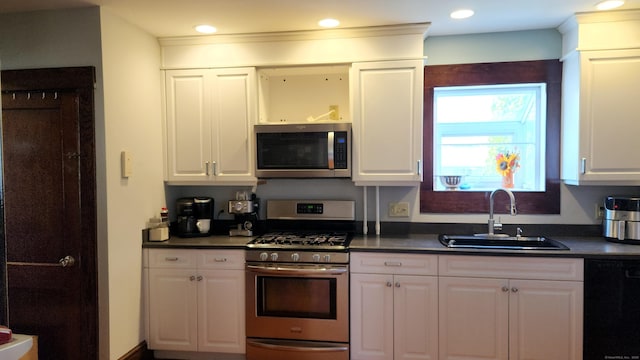 kitchen with white cabinetry, stainless steel appliances, dark countertops, and a sink