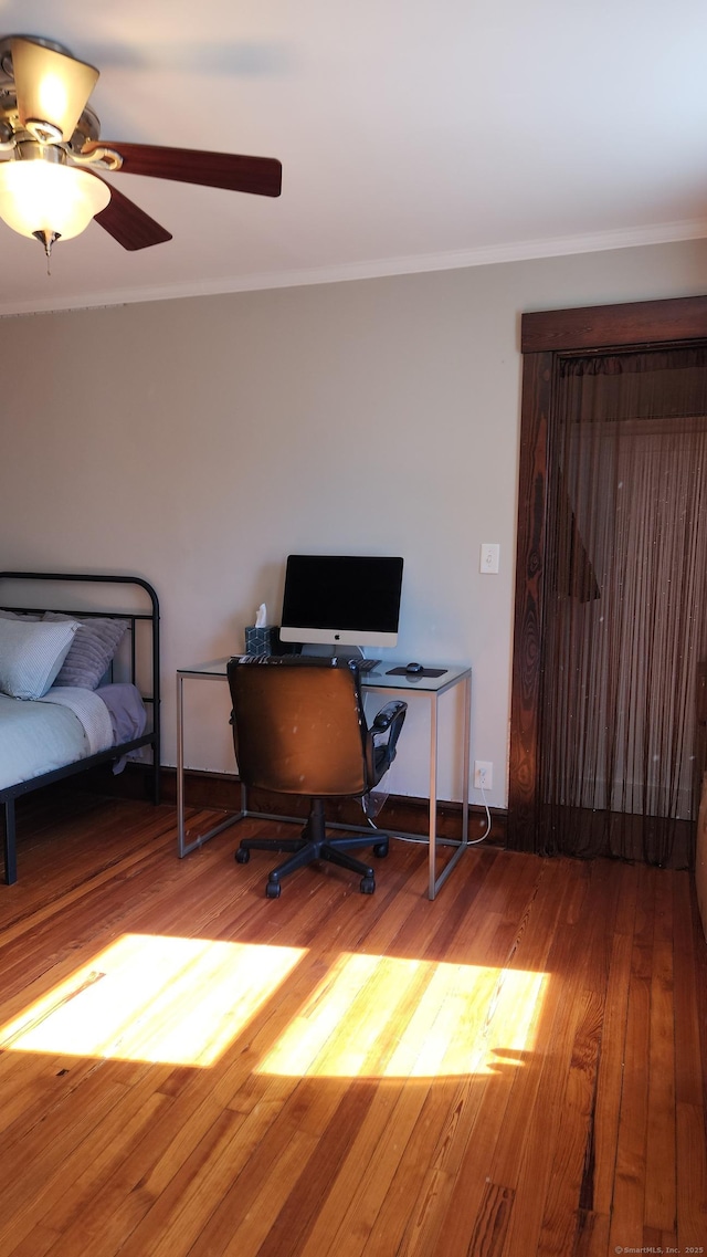 office space with baseboards, wood finished floors, a ceiling fan, and crown molding