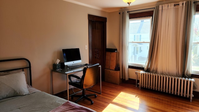 bedroom featuring wood finished floors, crown molding, and radiator