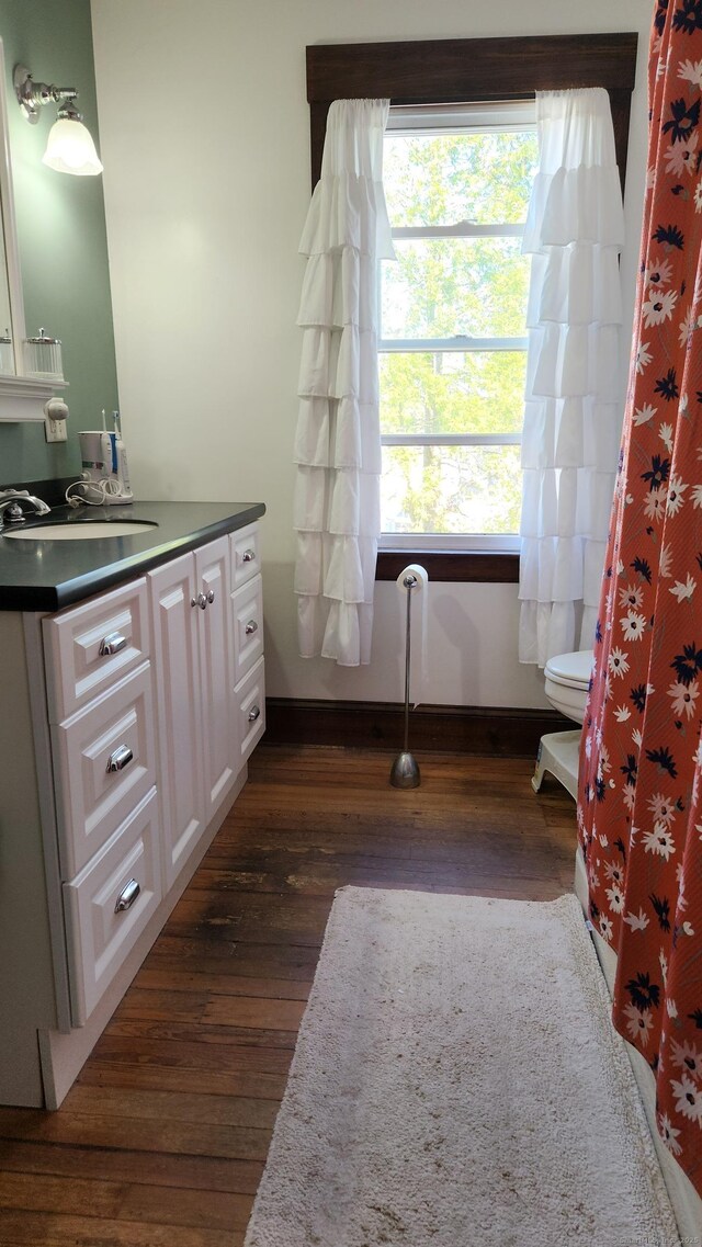 full bathroom with baseboards, wood finished floors, toilet, and vanity