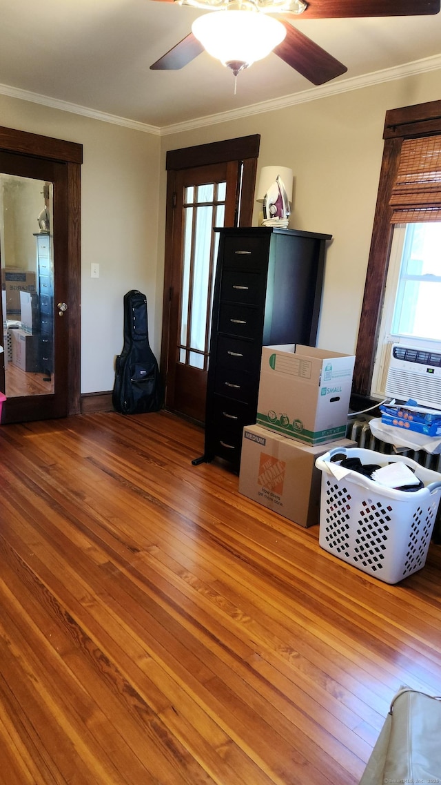 living room with wood finished floors, ceiling fan, crown molding, and cooling unit