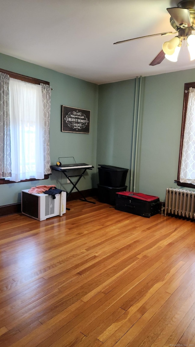 miscellaneous room with radiator, ceiling fan, and wood-type flooring