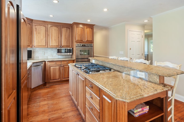 7 Tunxis Trl, Redding, CT 06896 - kitchen with a kitchen breakfast bar, light wood-style flooring, a center island, stainless steel appliances, and ornamental molding