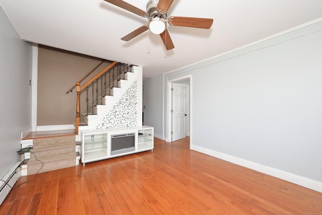 unfurnished living room with ceiling fan, light wood-style flooring, stairway, a baseboard heating unit, and baseboards