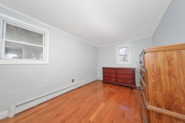 interior space with baseboard heating, a baseboard heating unit, ornamental molding, and wood finished floors