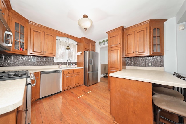 kitchen with brown cabinetry, a kitchen breakfast bar, a sink, and appliances with stainless steel finishes
