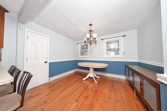 dining space with light wood-style floors, a notable chandelier, wainscoting, and baseboards