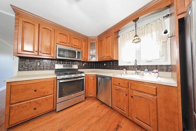 kitchen with brown cabinetry, light wood-type flooring, and stainless steel appliances