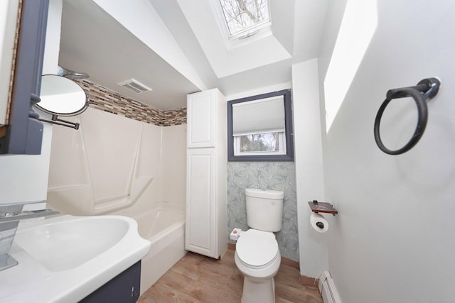 bathroom with visible vents, a sink, toilet, wood finished floors, and a skylight