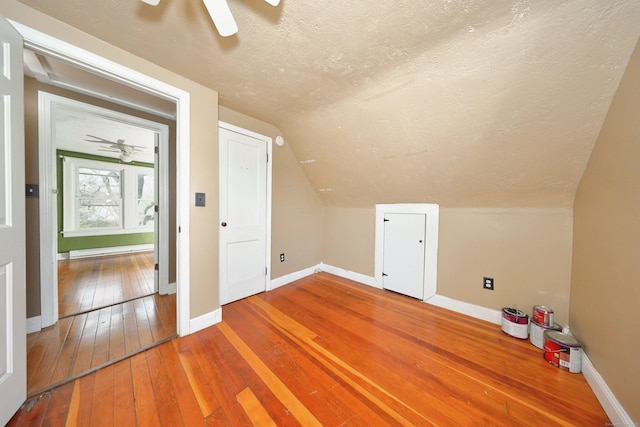 bonus room featuring hardwood / wood-style floors, baseboards, a ceiling fan, and a textured ceiling