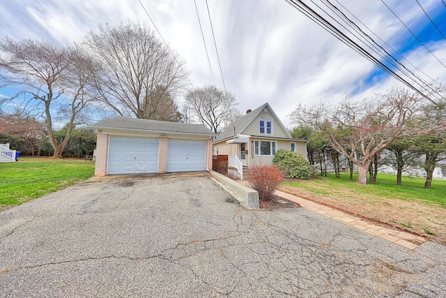 view of front facade featuring a detached garage and a front yard