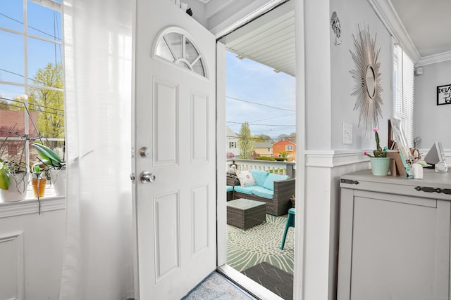 doorway with plenty of natural light, crown molding, and wainscoting