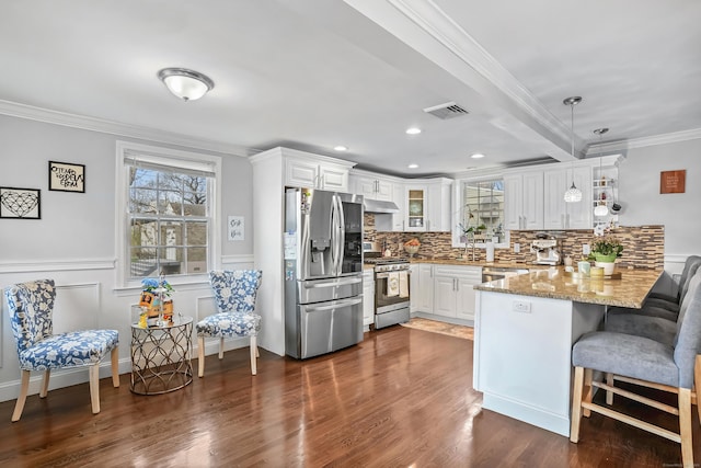 kitchen featuring white cabinets, stainless steel appliances, a peninsula, crown molding, and under cabinet range hood