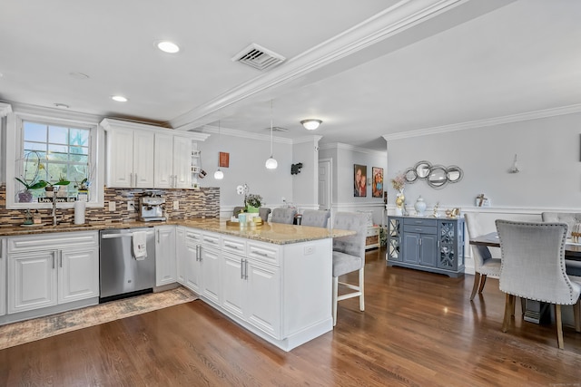 kitchen featuring stainless steel dishwasher, crown molding, a sink, a breakfast bar, and a peninsula