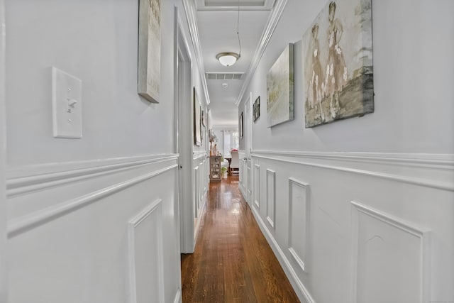 hallway with dark wood-style floors, a decorative wall, wainscoting, attic access, and visible vents