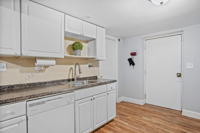 kitchen featuring dark countertops, white dishwasher, baseboards, and a sink