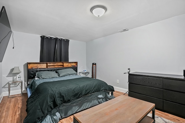 bedroom with baseboards, wood finished floors, and visible vents