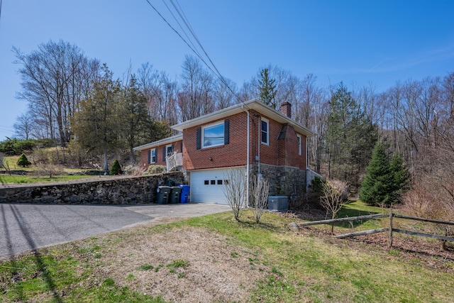 98 Aetna Ave, Torrington, CT 06790 - view of property exterior with a chimney, driveway, brick siding, a garage, and central AC unit