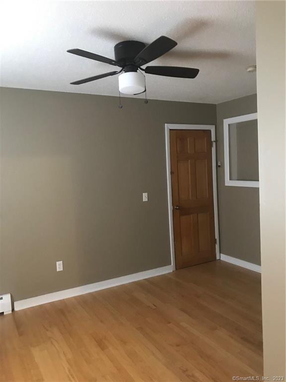 unfurnished room with light wood-style flooring, ceiling fan, and baseboards