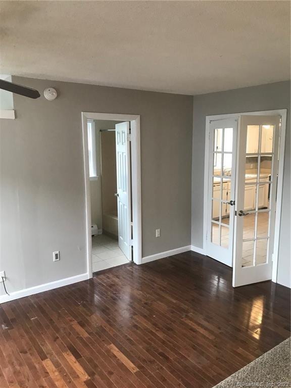 spare room featuring french doors, baseboards, and hardwood / wood-style floors
