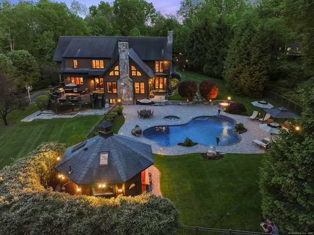 17 Fire Hill Ln, Redding, CT 06896 - back of property at dusk featuring an outdoor fire pit, a chimney, an outdoor pool, a patio area, and a jacuzzi