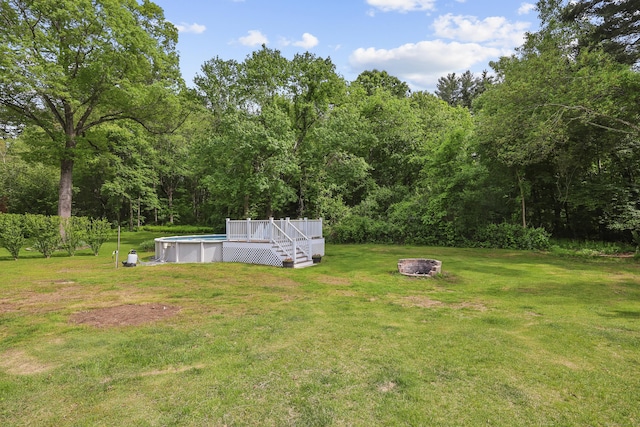 33 Jolley Rd, Plainfield, CT 06239 - view of green lawn featuring an outdoor fire pit, an outdoor pool, a wooden deck, and a wooded view